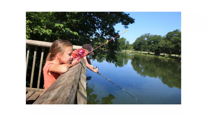 Kids with fishing poles at a pond